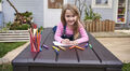 Girl is drawing and lying down on top of Keter storage box