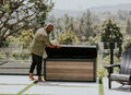 man opens his Keter signature 150 deck box outside on his patio