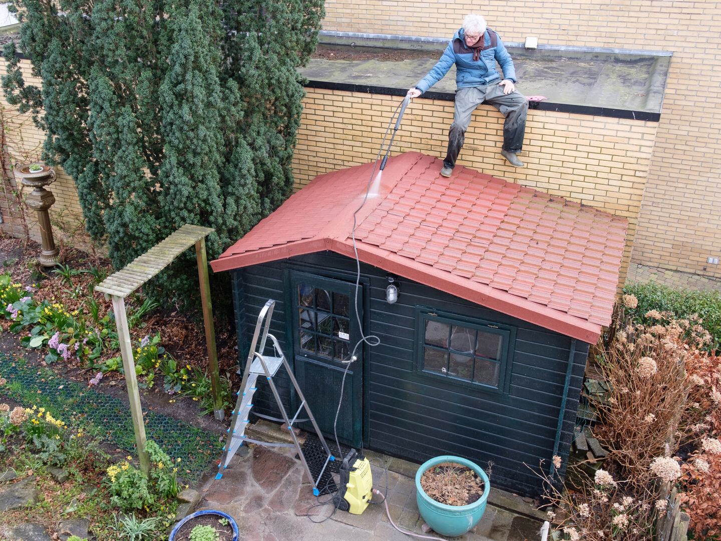 Man cleaning the roof of a shed